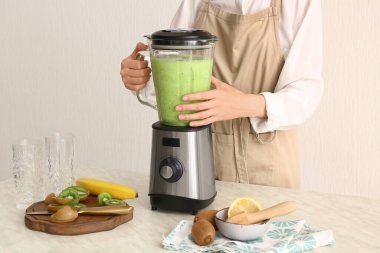 Kadın mutfakta taze kivi kokteyli hazırlıyor.