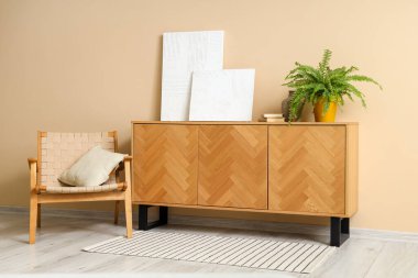 Oturma odasının içinde resimler, büfe ve rahat koltuklar var.