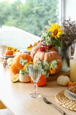 Yemek masasında balkabağı ve çiçeklerle sonbahar ayarı, yakın plan.