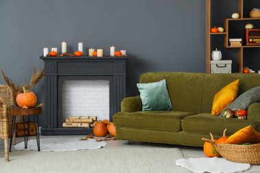 İçinde balkabakları, dekoratif şömine rafı ve kanepe olan bir oturma odası.