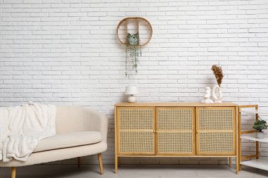 Raflı çekmeceler ve beyaz tuğla duvarın yanındaki kanepe.