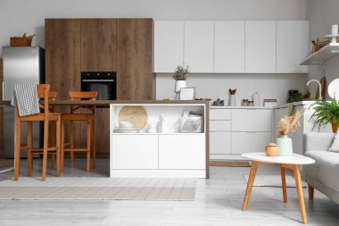 Beyaz mobilyaları ve ada masası olan modern mutfağın içi.