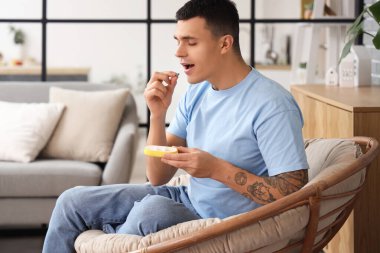 Evdeki ilaç kutusundan hap alan genç bir adam.