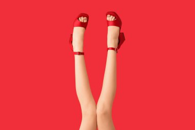 Kırmızı arka planda şık topuklu güzel genç bayanların bacakları.