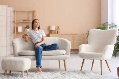 Oturma odasındaki kanepede dinlenen genç ve güzel bir kadın.