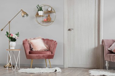 Pembe koltuğu, yastıkları, lambası ve sehpası olan güzel bir oturma odası.