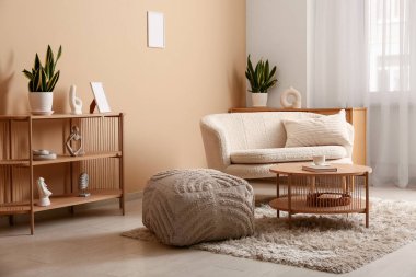 Rahat bir kanepe, büyük bir puf ve oturma odasında kitap ve bir fincan çay ile kahve masası.