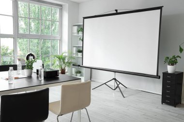 Projektör ekranı ve toplantı tablosu olan ofis içi