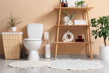 Tuvaletin içinde klozet, raf ünitesi ve çamaşır sepeti var.