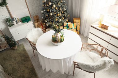 Masası, çekmecesi ve Noel ağacı olan yemek odasının içi.