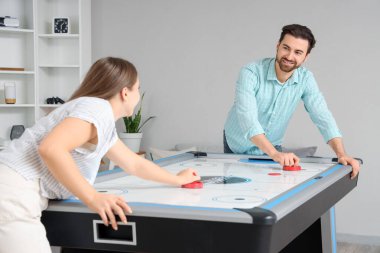 Genç adam ve kız arkadaşı evde hokey oynuyorlar.