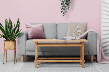 Oturma odasının iç tarafındaki pembe duvarın yanındaki masa ve kanepe.