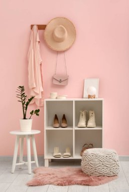 Koridorun iç tarafındaki pembe duvarın yanında dur ve pouf.