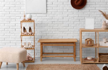 Raflar, bank ve ayakkabılar koridorun iç tarafındaki beyaz tuğla duvarın yanında duruyor.