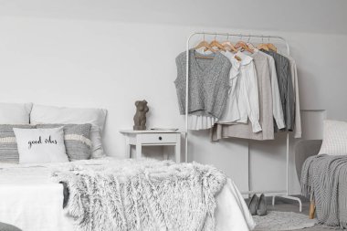 Yatak odasının içinde rahat bir yatak ve kıyafetlerle dizilin.