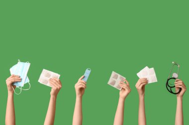 Female hands with mustard plasters, stethoscope, pill box and medical mask on green background