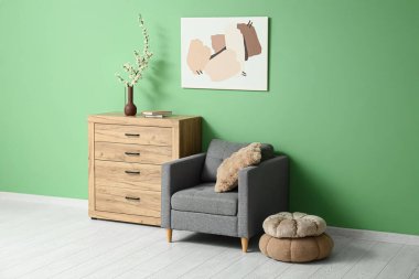 Gri koltuklu, puflu ve ağaç dallı ahşap şifoniyerli şık bir oturma odası.