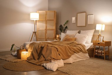 Akşamları çerçeveli, çiçekli ve parlayan lambalı rahat bir yatak odası.