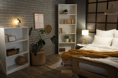 Şık bir yatak odası, rahat bir yatak odası, raf üniteleri ve akşam lambaları.