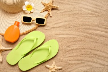 Composition with stylish beach accessories, bottle of sunscreen and starfishes on sand