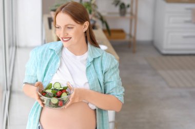 Evde sebze salatalı hamile bir kadın var.