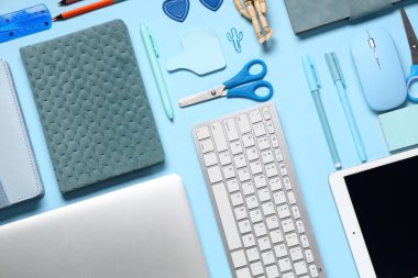 Mavi arka planda modern dizüstü bilgisayar, klavye, tablet bilgisayar ve okul malzemeleri ile kompozisyon
