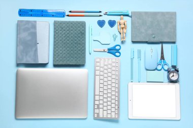 Mavi arka planda modern dizüstü bilgisayar, klavye, tablet bilgisayar ve okul malzemeleri ile kompozisyon