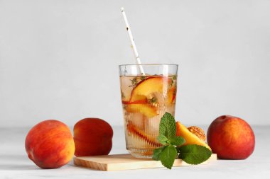 Bir bardak taze şeftalili limonata kekik ve beyaz arka planda nane şekeri.