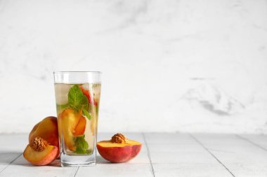 Bir bardak taze şeftali, naneli limonata ve beyaz fayanslı meyveler.