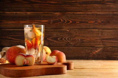 Bir bardak taze şeftalili limonata kekik ve ahşap arka planda meyveler.