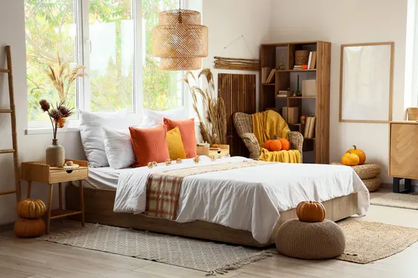 Yatak, koltuk, yastık ve balkabağı olan rahat bir yatak odası.