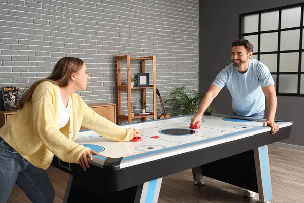 Mutlu genç çift evde hokey oynuyor.