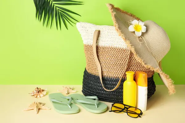 Hasır çanta, güneş kremi şişeleri ve arka planda plaj aksesuarları, yakın plan.