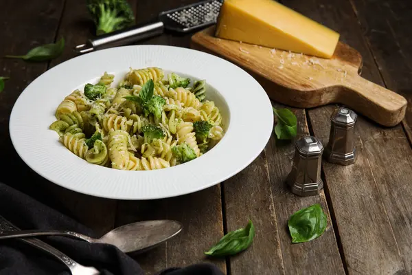Tahta zemin üzerinde brokoli ve fesleğen yapraklı lezzetli fusilli makarna.