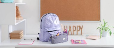 Okul gereçleri, tahta ve sırt çantalı çalışma alanı beyaz duvarın yanında.