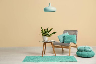 İçinde sandalye, puf, masa ve sansevieria bitkisi olan oda. Bej duvarın yanında.