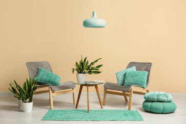 İçinde sandalyeler, masa, puf ve sansevieria bitkileri olan bir oda.