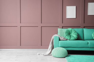 Naneli kanepe ve puf, oturma odasının iç tarafındaki kahverengi duvarın yanında. Tasarım için pankart