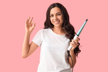 Pembe arka planda saç maşası olan güzel bir kadın.