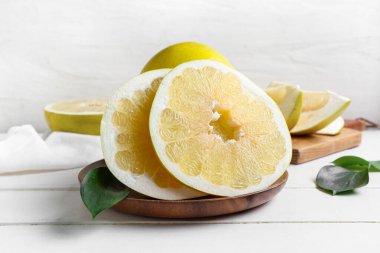 Beyaz ahşap masa üzerinde taze meyve ve yapraklarla dolu bir tabak.