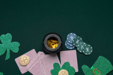 Poker fişleri, kartlar, yoncalar ve koyu yeşil arka planda bozuk paralar. Aziz Patrick Günü kutlaması