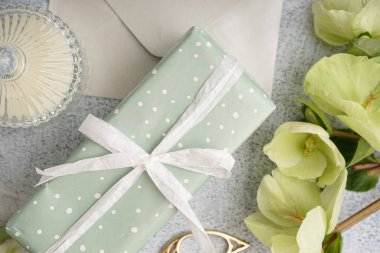 İçinde güzel çiçekler, zarf ve arkaplanda mum olan hediye kutusu.