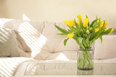 Oturma odasındaki cam sehpanın üzerinde laleler olan vazo.