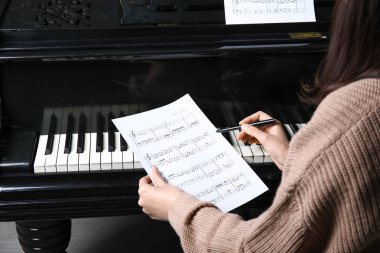 Piyanoyla müzik besteleyen genç kadın.