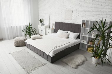 Büyük yataklı, çekmeceli ve palmiye ağaçlı şık bir yatak odası.