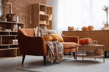 Sonbahar dekoru, kırmızı kanepesi ve masası olan rahat bir oturma odası.