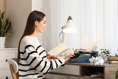 Masada oturan daktilo ve not defteriyle güzel, mutlu kadın yazar.