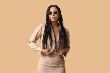 Bej arka planda örgüleri olan şık Afro-Amerikan kadın.