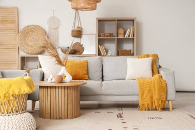 Oturma odasının içinde gri kanepe ve sehpanın üzerinde pampalar var.