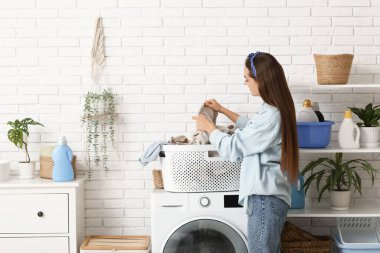 Evinde bir sepet temiz çamaşırları olan güzel, genç bir kadın.